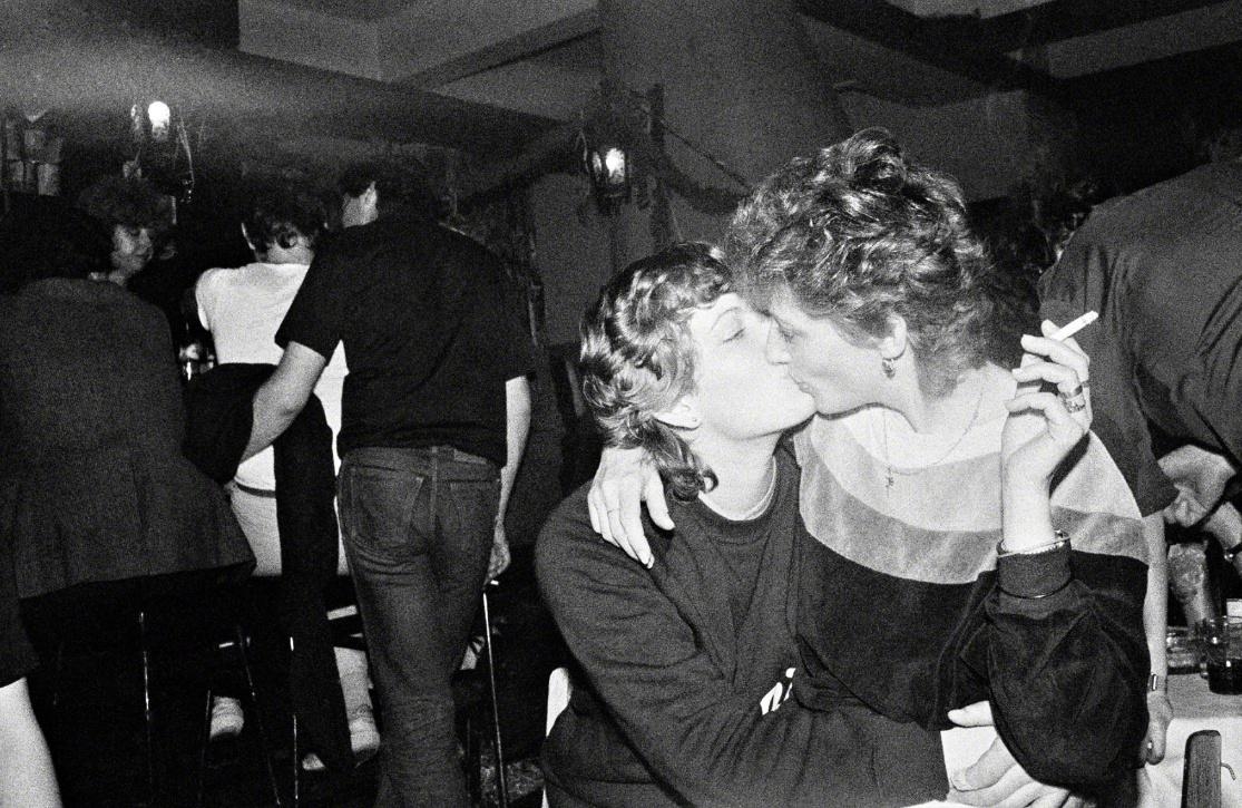 Two women kissing in a nightclub.