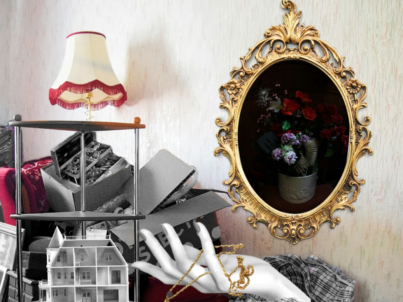 Crop of a larger colourful photograph with some coloured and black and white collage elements. The photo is of an empty living room with patterned off-white wallpaper, a red floral patterned sofa and a patterned carpet. There are pieces of black and white furniture in a pile next to and on top of the red sofa, including lamps, picture frames, storage bags, jewellery boxes and a shelving unit. On the shelving unit is a three story dollhouse which is empty. A black and white mannequin hand is shown coming out of a storage bag, and laced between its fingers is a golden pendant which is open and contains a photo of a girl and her grandma. On the wall is a ornate golden photo frame that contains a photo of a vase of different coloured flowers and a hairbrush.