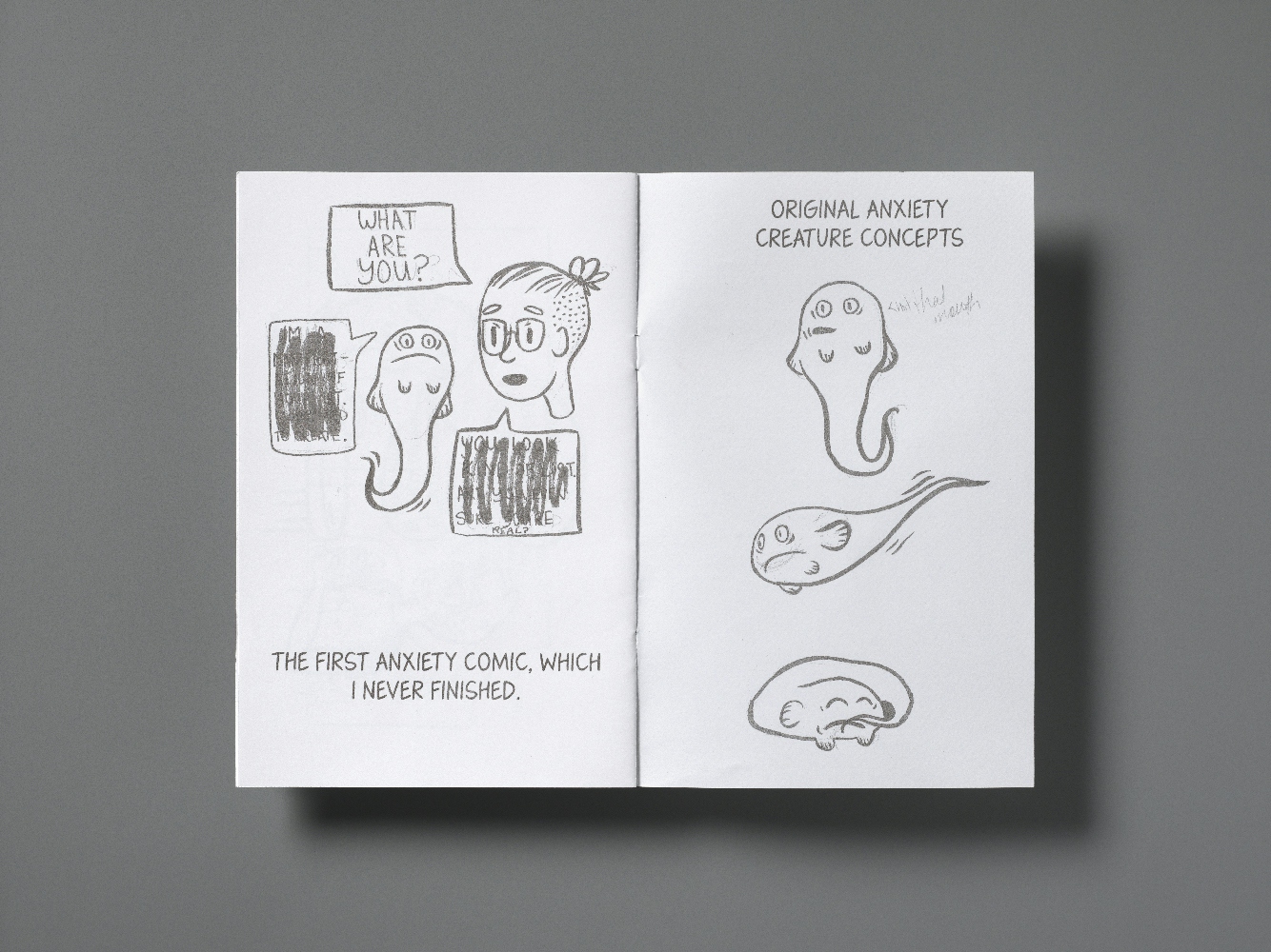 A double page spread from a comic-zine called Anxiety Comics Vol. 1. The left page shows a young woman's head with a speech bubble saying "What are you?" as she looks at an anxious looking fish-like creature. Two other speech bubbles on the page have been crossed out so the text is unreadable. Text below the image says "The first anxiety comic, which I never finished." The righthand page has text at the top saying "Original anxiety creature concepts". Below it are three illustrations of the 'fish' creature still, swimming and curled up asleep.