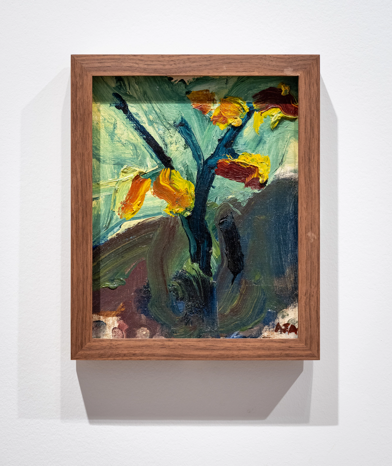 Photograph of an oil painting of daffodils framed on a gallery wall.