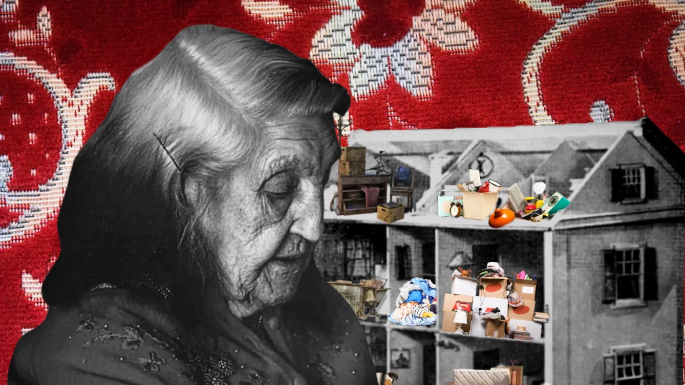 Colourful digital collage. In the foreground is a black and white photograph cut-out of an elderly woman looking downwards. A bobby pin pulls back the grey hair around her right ear. She is wearing a flowery embroidered shawl. Behind the elderly woman and within her eye line is a black and white cut out of a three story toy dollhouse. The walls and roof of one side of the dollhouse have been removed, exposing the interior of the house. Inside the dollhouse in the different rooms there are many small, colourful cut outs of household objects and furniture, including an alarm clock, wooden chests of drawers, filled cardboard boxes, piles of books and bed sheets. The objects are stacked on top of each other messily, forming many piles. The background is a photograph of a red and white floral print. 