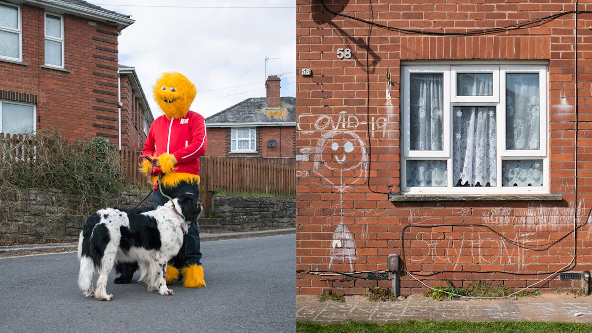 A photographic diptych. The image on the left shows an adult wearing a furry yellow Honey Monster costume, including a red tracksuit top and blue tracksuit bottoms standing in a residential road with red brick houses beyond. The Honey Monster is holding a large black and white dog facing away from camera. The image on the right shows a section of the ground floor of a red brick house with a white PVC door and window with net curtains. On the brick wall surrounding the window there is a large chalk drawing of a stick person with Covid-19 written above it. Beneath the window is written ‘stay home’. 