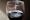 Photograph of wine glass containing red wine. on the surface and around the lip of the glass are lipstick and finger print marks.