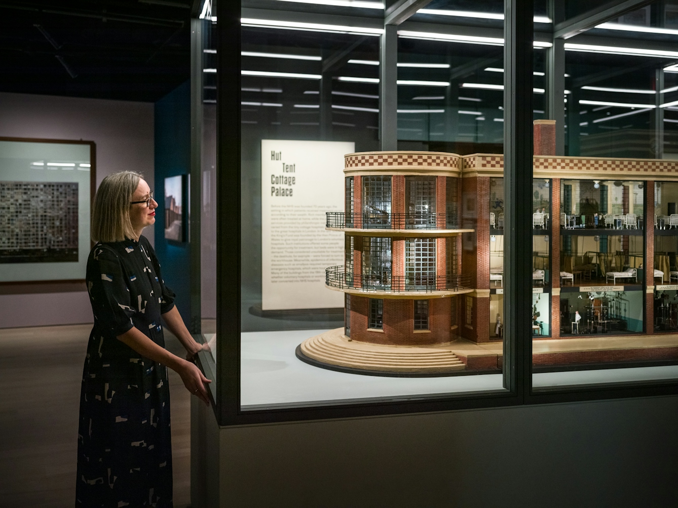 Photograph of curator Emily Sargent looking at a large architectural model in the exhibition Living with Buildings at Wellcome Collection.