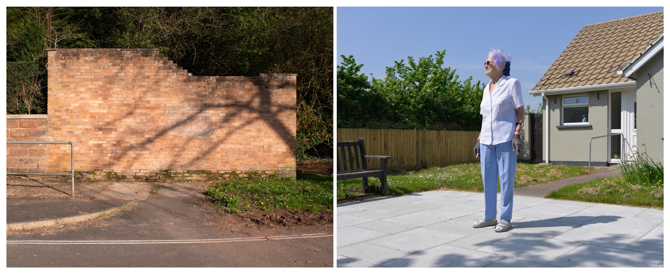A photographic diptych. The image on the left shows a yellow brick garden wall on which a long shadow of a tree and its branches are cast. The image is taken from the road and shows a concrete path and handrail to the left, and a small patch of grass verge to the right. The image on the right shows a paved area with a wooden bench. Beyond that is a concrete path with a handrail between a lawn strewn with daisies, leading to a small grey bungalow. On the paved area in the foreground stands a tall elderly woman looking off to the left wearing blue trousers, a light blue short sleeved shirt, and gardening gloves. She is also wearing small round sunglasses, and has short grey/purple fluffy hair