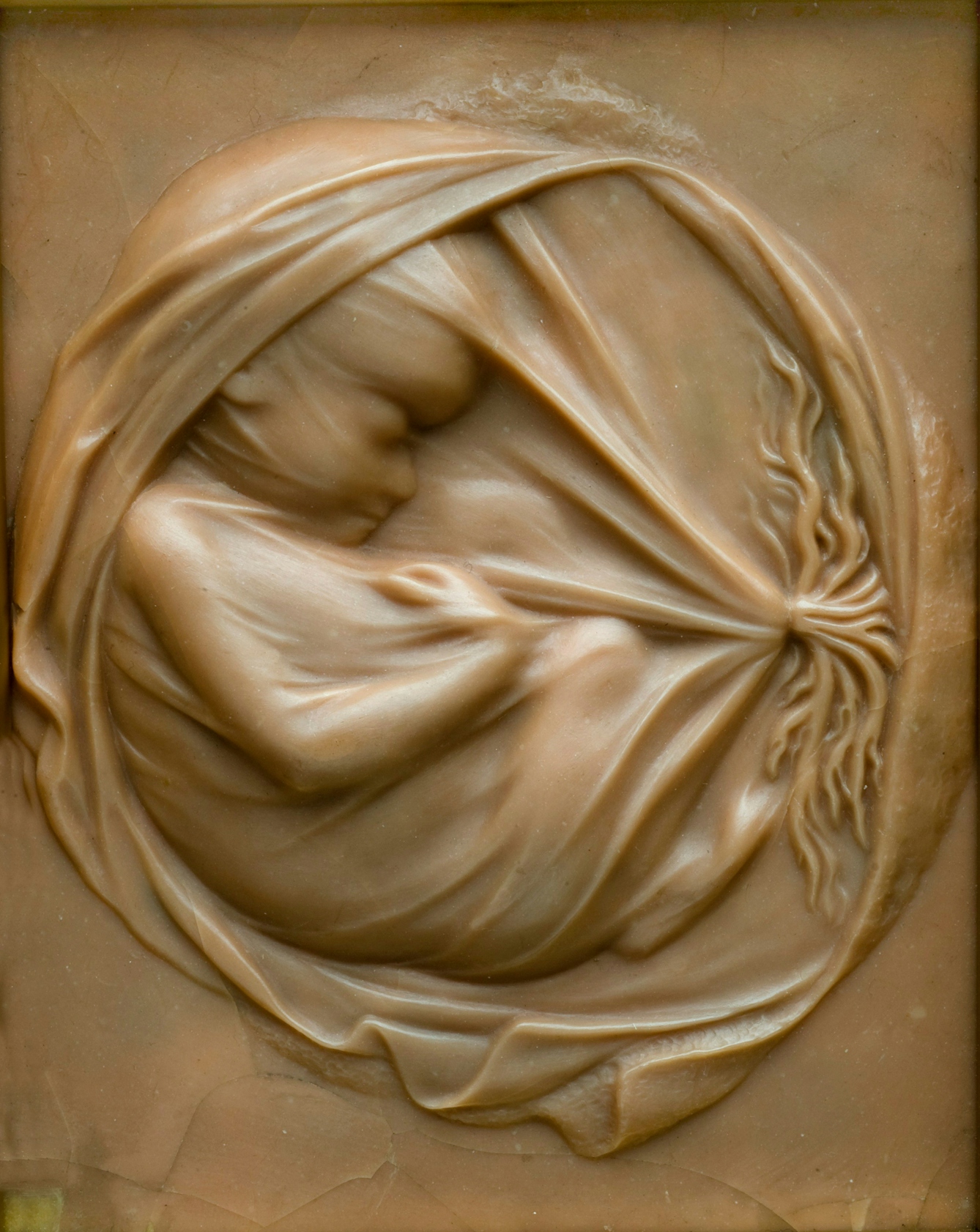 A photograph of a sculpture in wax. The small plaque illustrates a well developed foetus. Shrouded ghostlike within a membranous covering, it appears to be sleeping. 