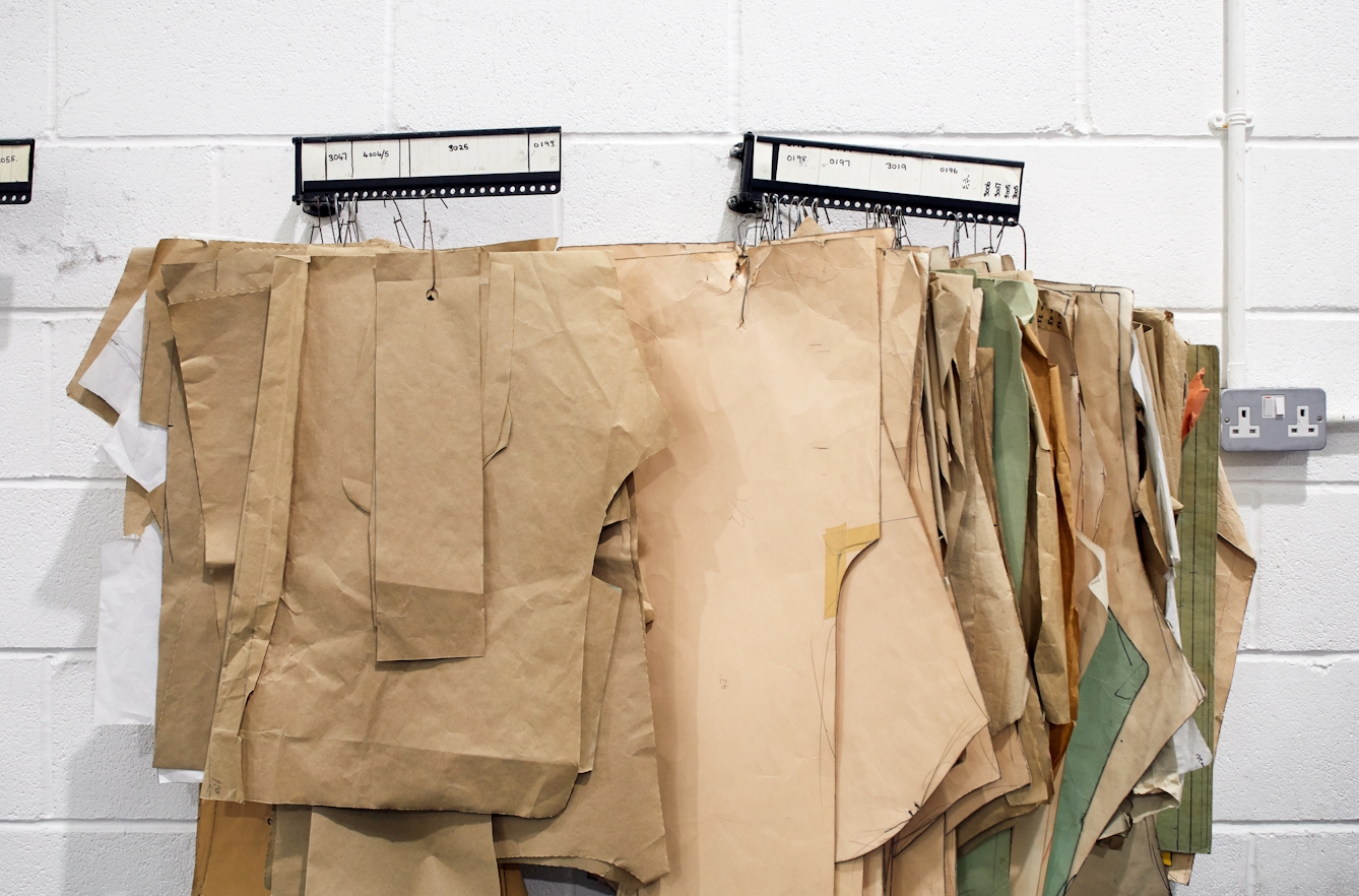 Photograph of paper cutting patterns hanging against a white brick wall.