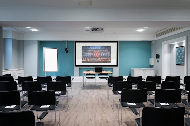 Photograph of the Franks room at the Wellcome Collection. 

Photograph shows a theatre space with chair, a whiteboard and a projector and screen set-up. 