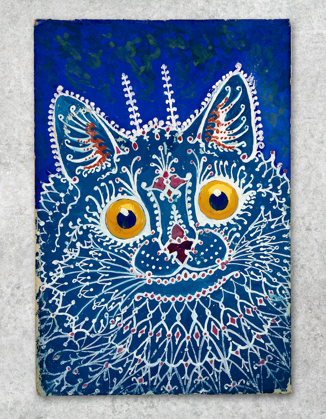 Photograph showing a work of art against a grey concrete textured background. The artwork shows colourful, abstract interpretation of a cat in tones of blue, white and yellow, by Louis Wain. On a blue ground, a turquoise cat, the patterns of its fur being formed by white lines resembling gothic tracery