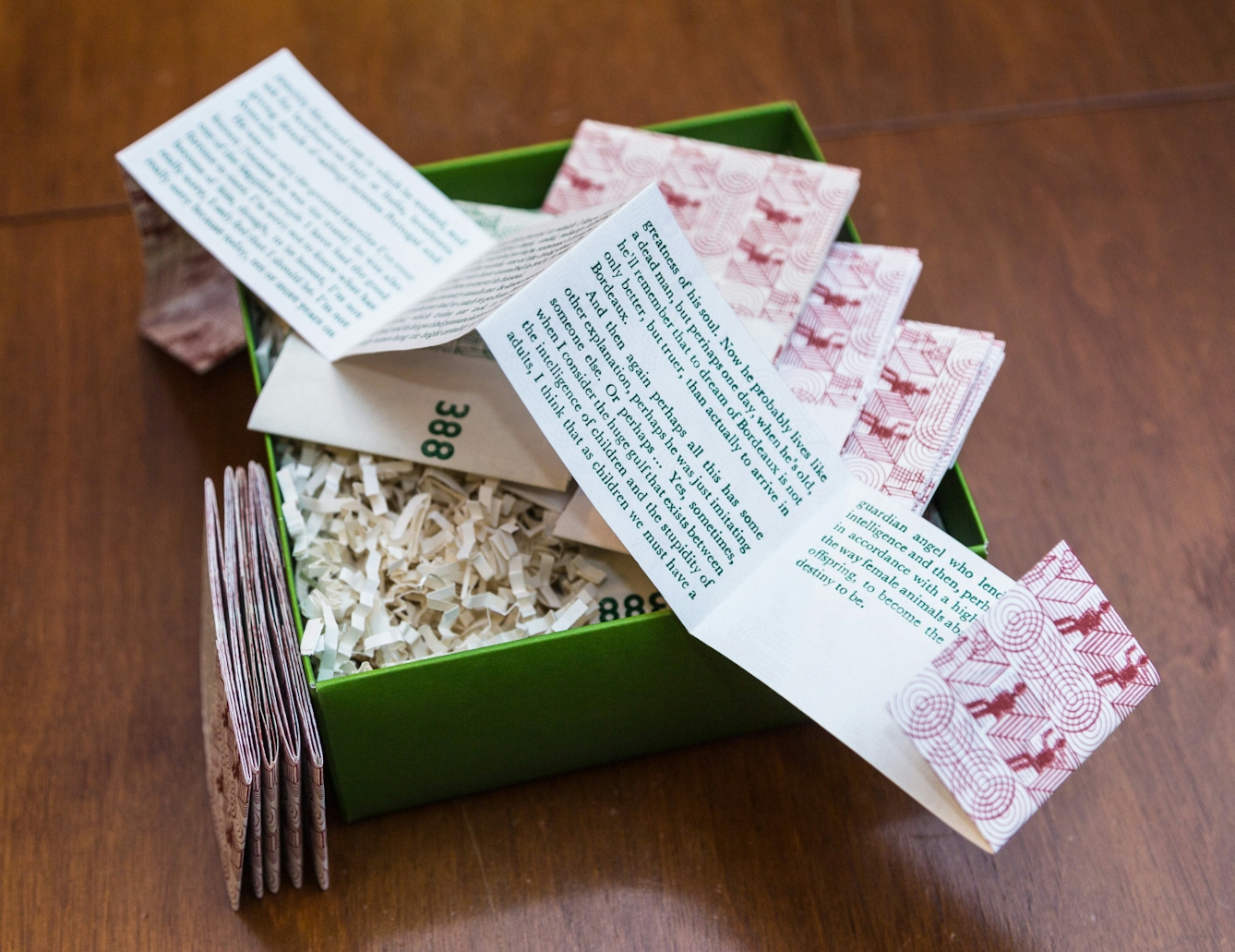 An unfolded, printed piece of card sits on top of a small, bright green box.