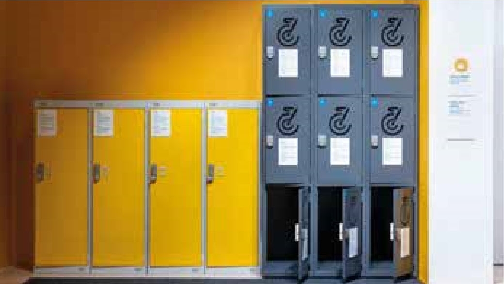 Four large bright yellow metal lockers in a row next to nine smaller grey lockers, stacked in three rows of three.