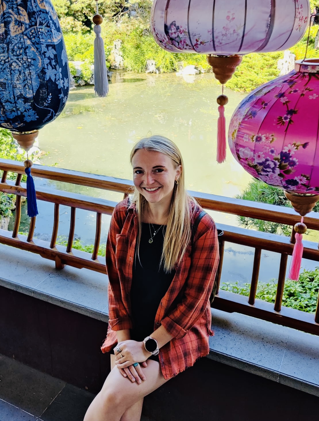 A photo of Daisy Watson Shaw sitting and smiling with a lake behind her.