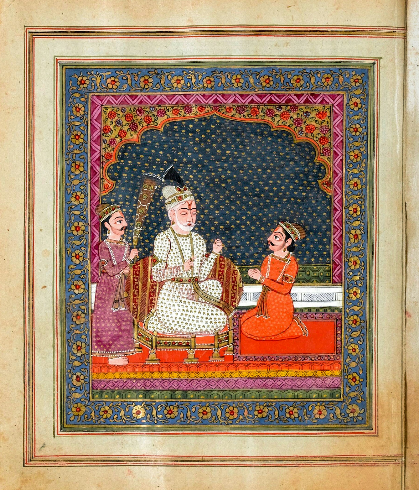 Photograph of an ornately illustrated Panjabi manuscript. The illustration is intricately detailed in vibrant colours, including reds, oranges and blues. It depicts a scene where a central character in white has his eyes closed, listening to an individual in orange, kneeling in-front of him. The central character is being fanned by an individual in purple to the left. The scene is framed by beautiful drawings of flowers and patterns.