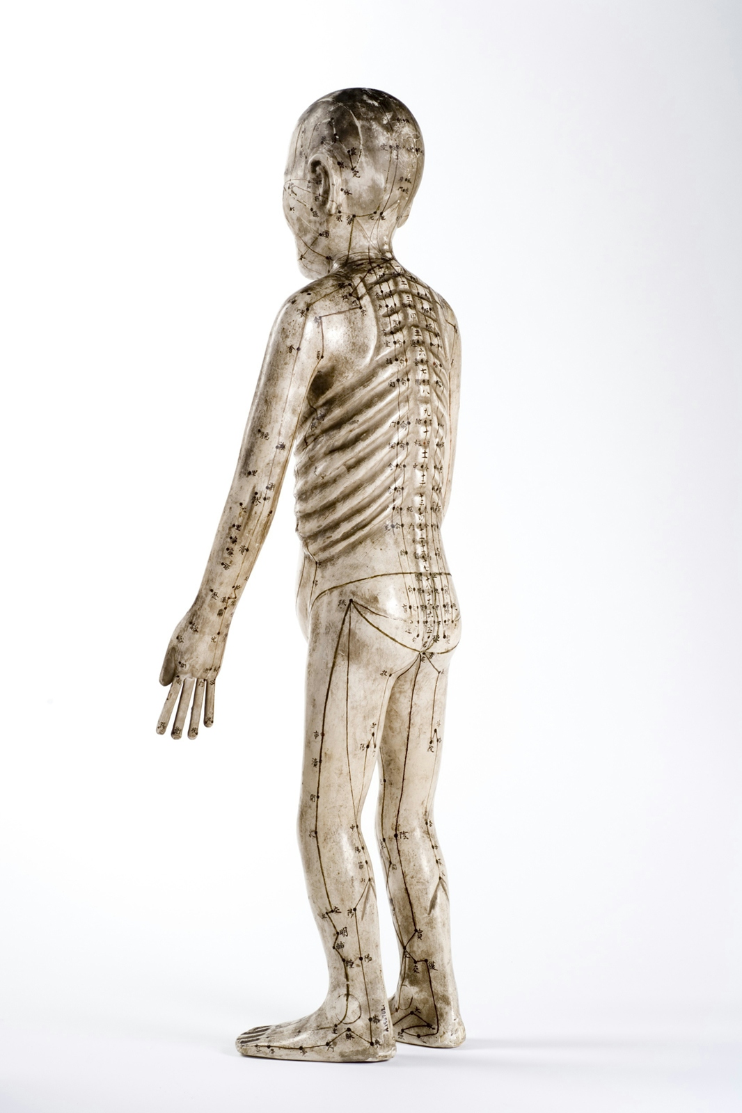 An image of a human figure made from papier mache with acupuncture points marked on it.