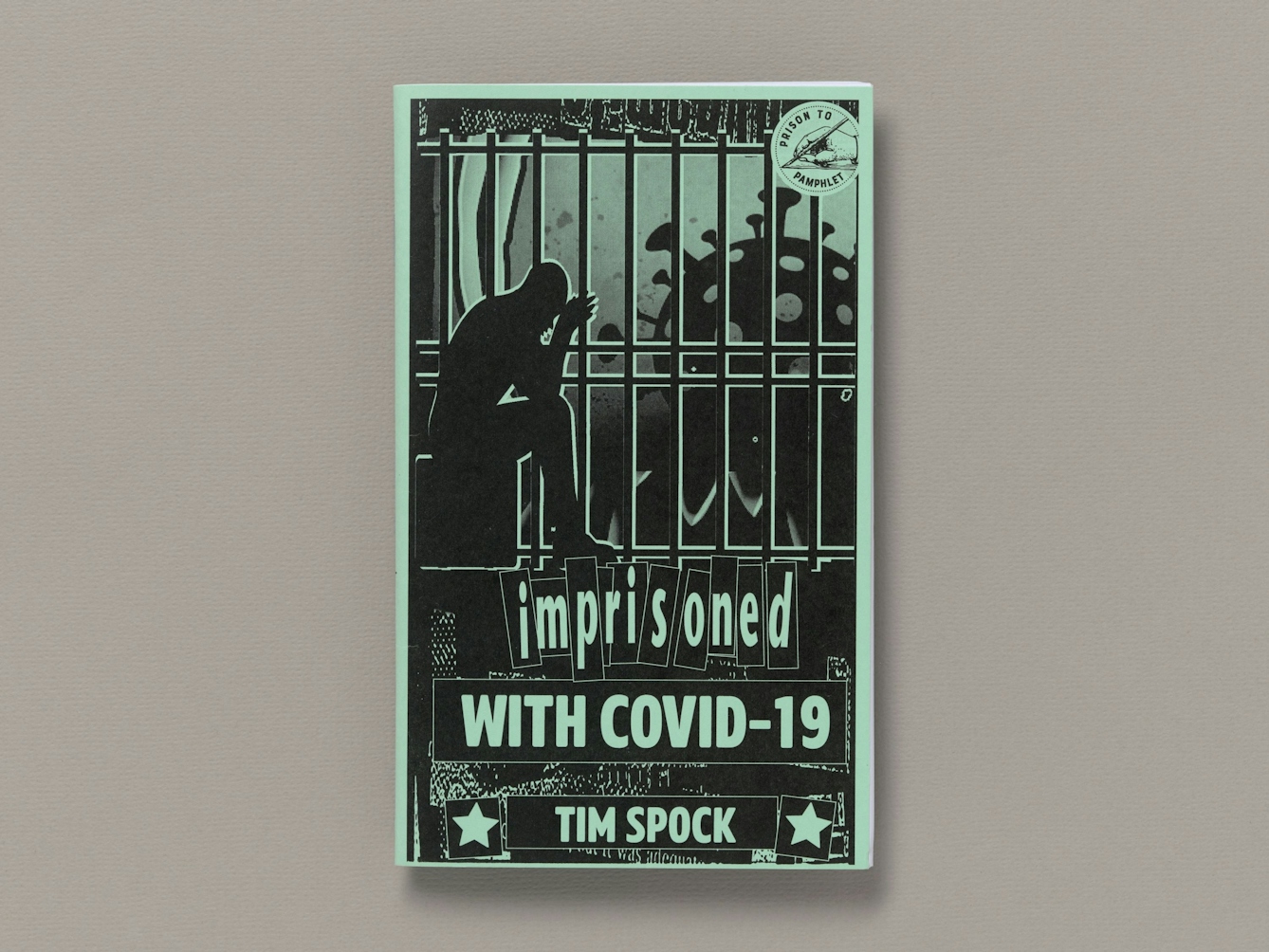 The front cover of a zine called "Imprisoned wiwth COVID-19' by Tim Spok. Teh cover shows the silohuette of a figure sat iwth his head in his hands behind prison bars. On the other side of the bars is the giant silohuette of the COVID-19 virus.