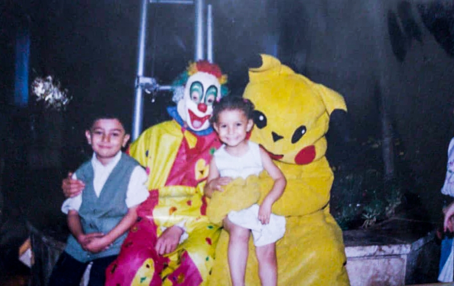 Photograph of two children sitting with two adults dressed in large colourful children's character costumes.