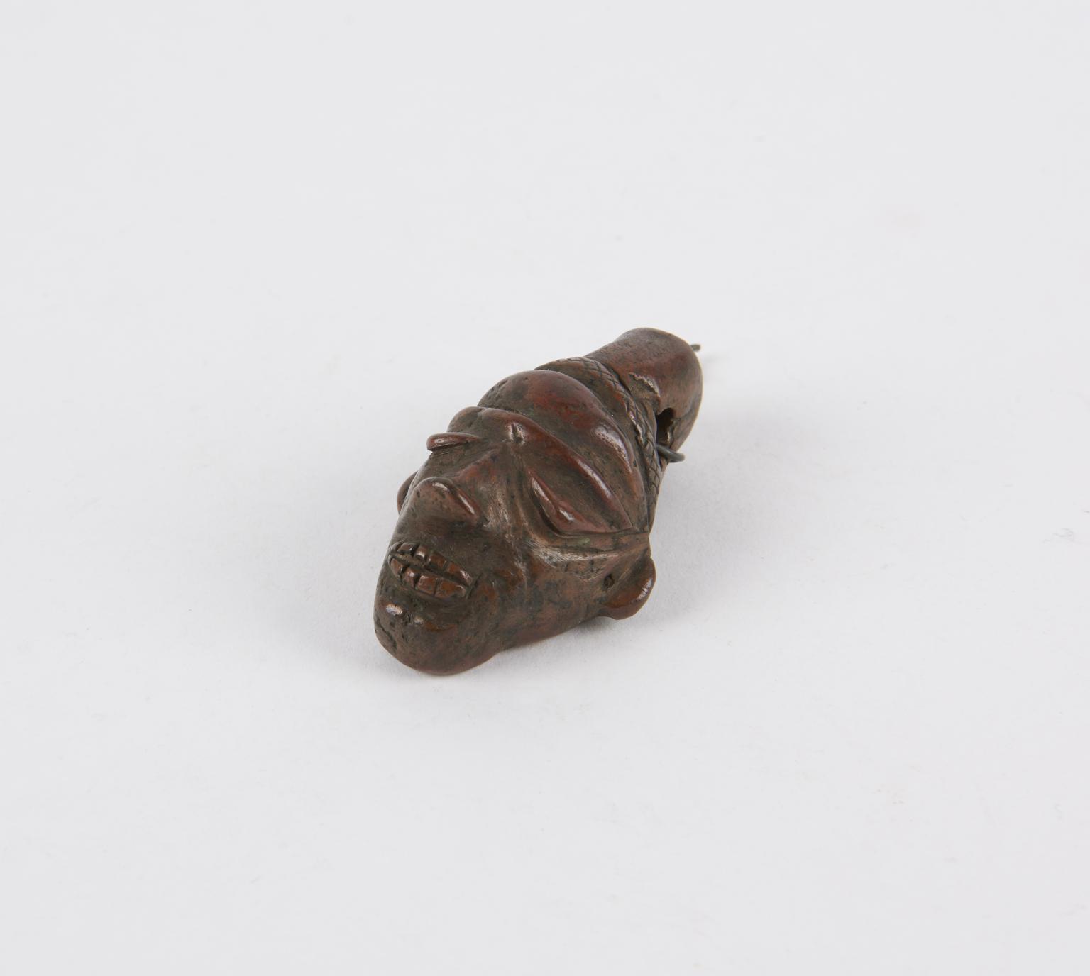 Small copper amuletic mask depicting a human face, created by the Babunda people of the Kasai River region in Congo between 1800 and 1920. 