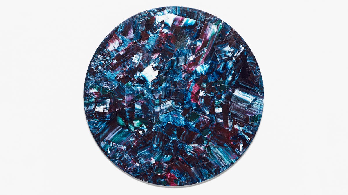Photograph of an abstract expressionist painting  utilising acrylic paint on a circular canvas, titled 'Dissonant'. The artwork explores themes of disharmony and discordance in relation to the disabled lived experience.

The vast majority of the canvas surface contains sharp disconnected marks of blues, purples, turquoise, white and scarlet. The marks are short and random in direction and length. Together they make up a scene of fractured and abrupt expression, yet with a compelling beauty.