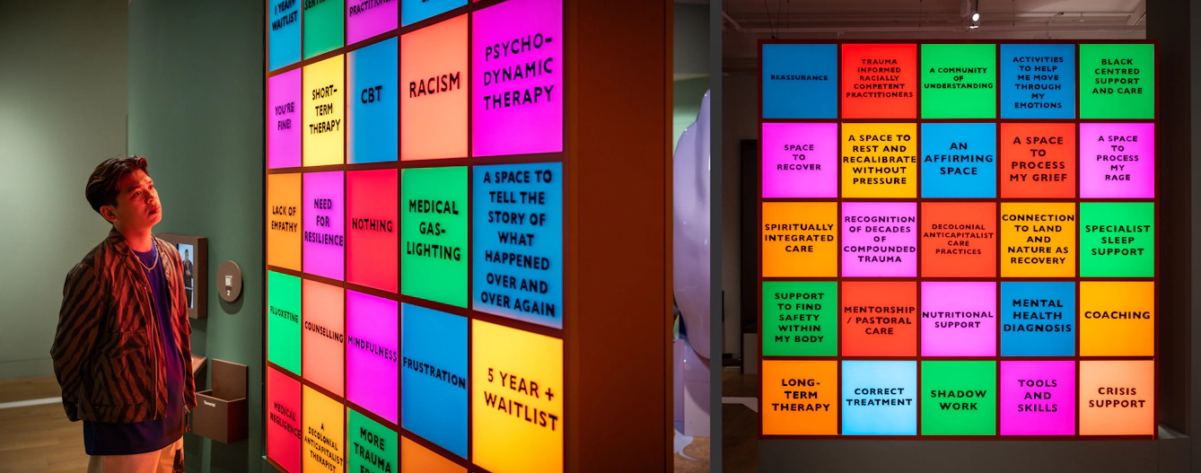 Photographic diptych of a gallery visitor, on the left, looking at a large illuminated artwork showing a grid of 5 by 5 coloured squares with text written on the front. Some of the words read, 'Racism', CBT', 'Nothing', and 'Frustration'. The image on the right shows the reverse of the artwork which is identical except that the selection of words have changed.