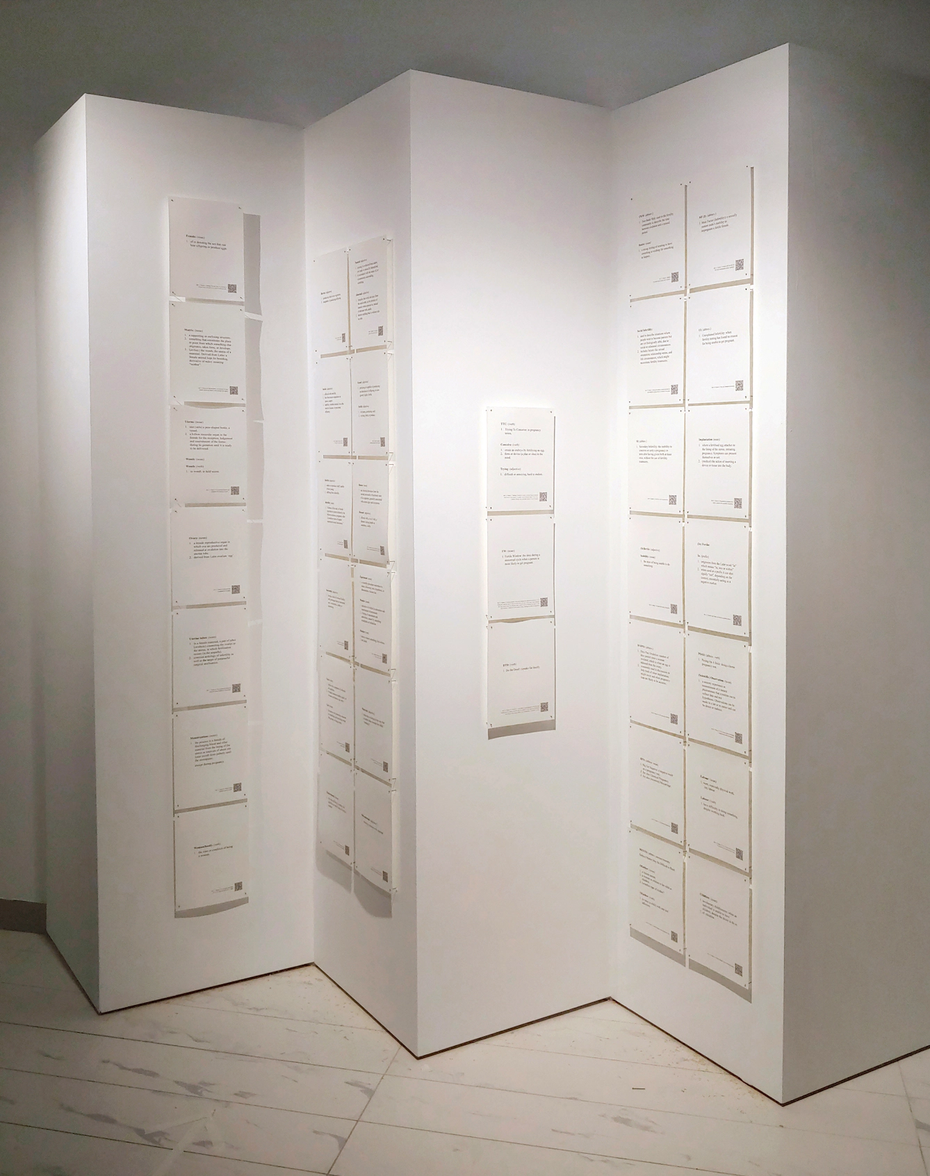 A concertina screen with pages of text pinned to all of the panels. Part of 'A Glossary With(in)Fertile Terms', an artwork by Sally Butcher.