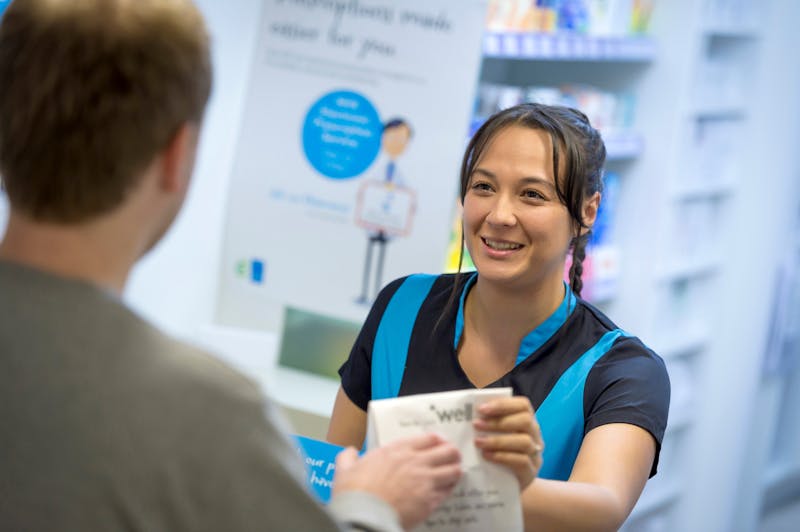A pharmacy colleague handing a customer medicines