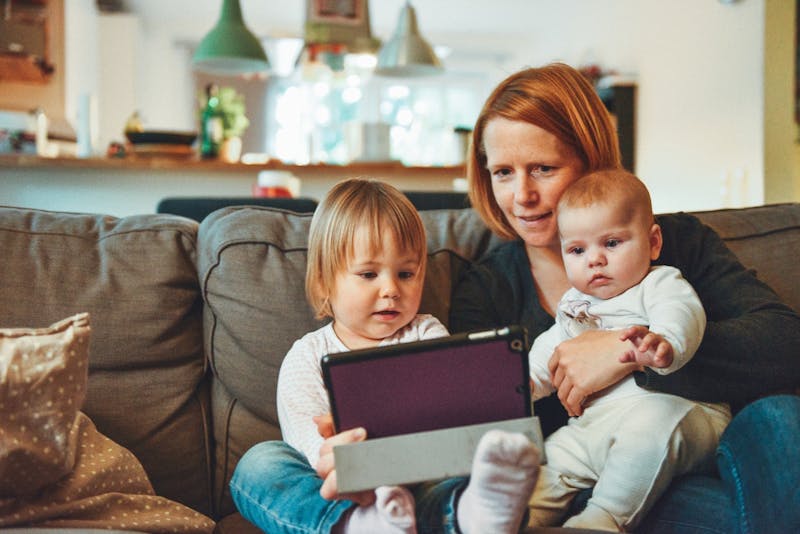 Woman and two young children on a sofa looking at a tablet computer.
