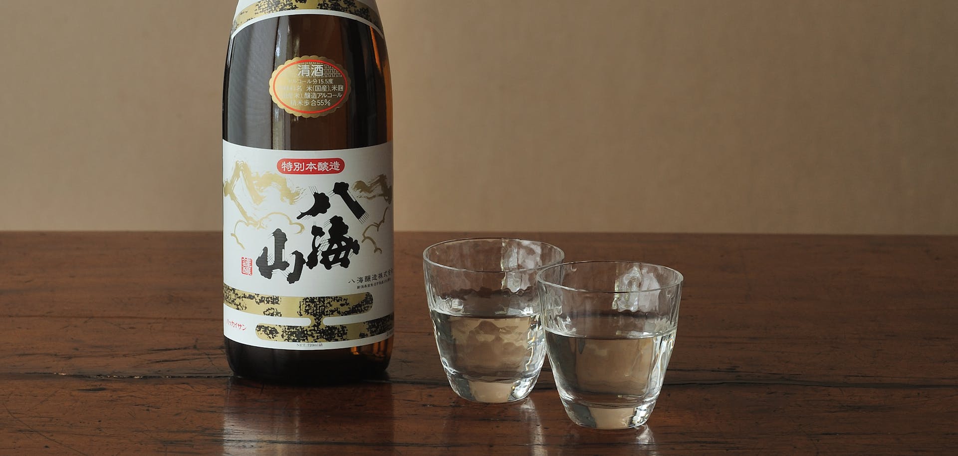 Bouteille de saké accompagnée de deux verres à dégustation sur une table en bois