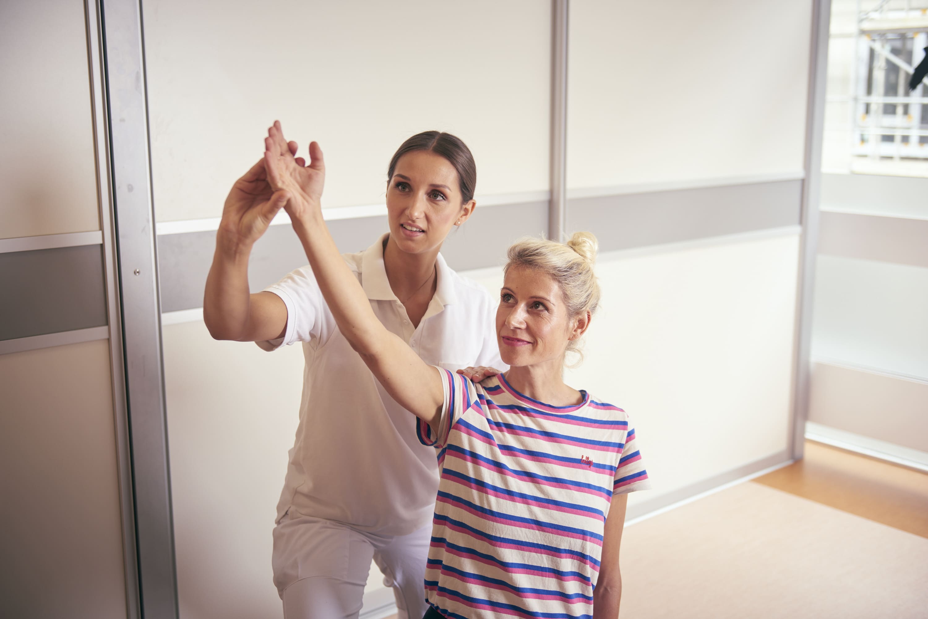 Patientin mit Arthritis dehnt ihren Arm bei der Physiotherapie in der Wicker Klinik
