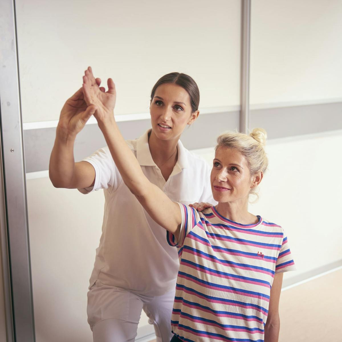 Patientin mit Arthritis dehnt ihren Arm bei der Physiotherapie in der Wicker Klinik