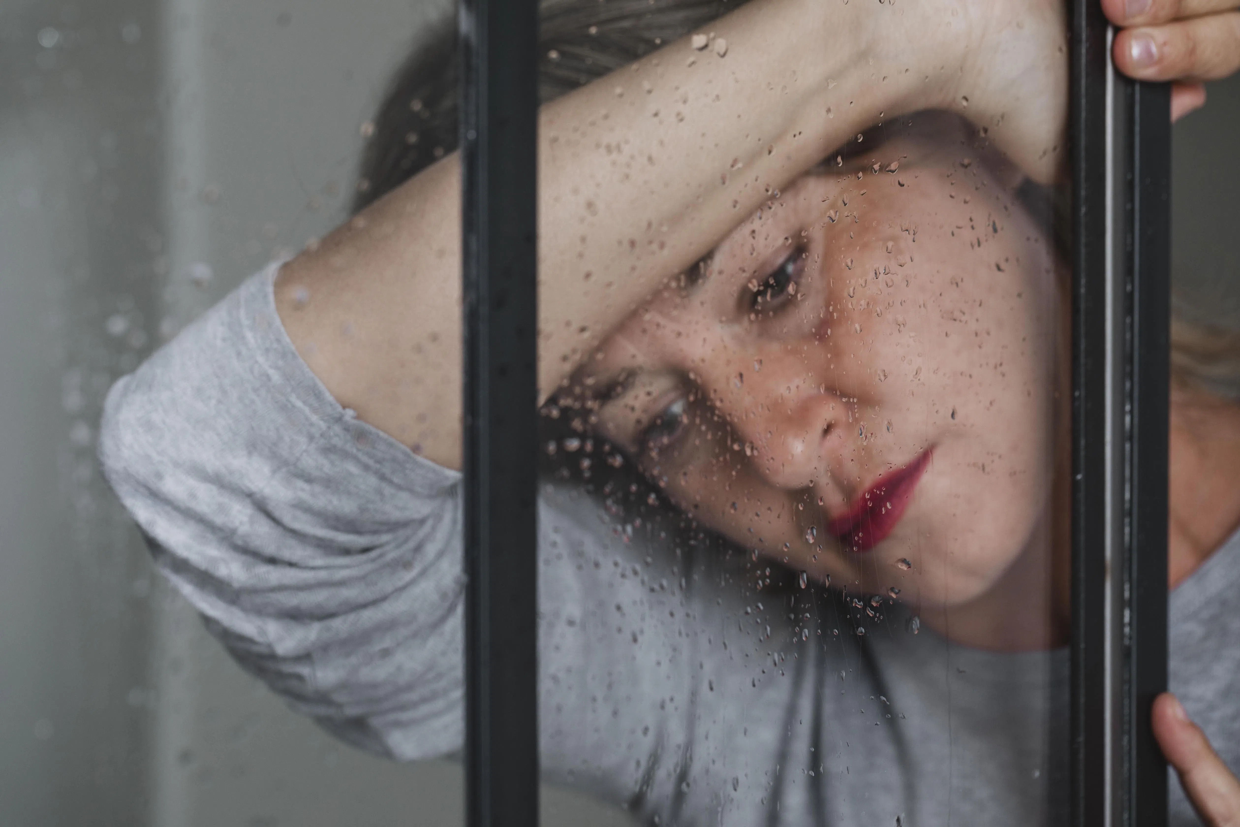 Frau steht traurig am Fenster