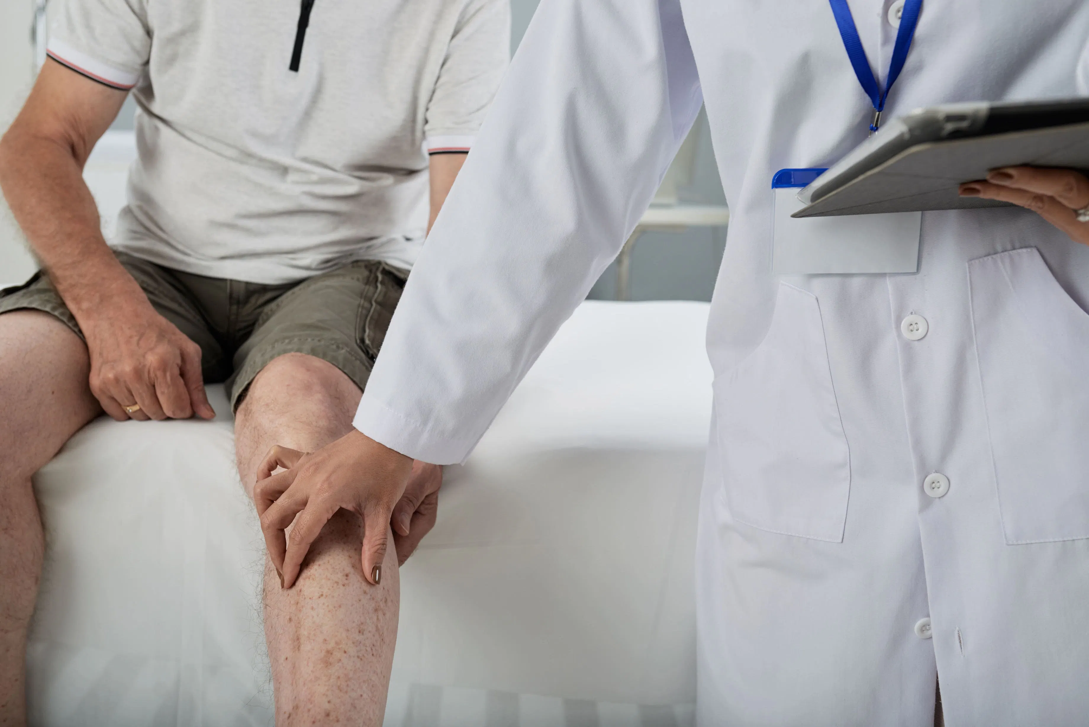Arzt untersucht das Knie eines Arthrose Patienten