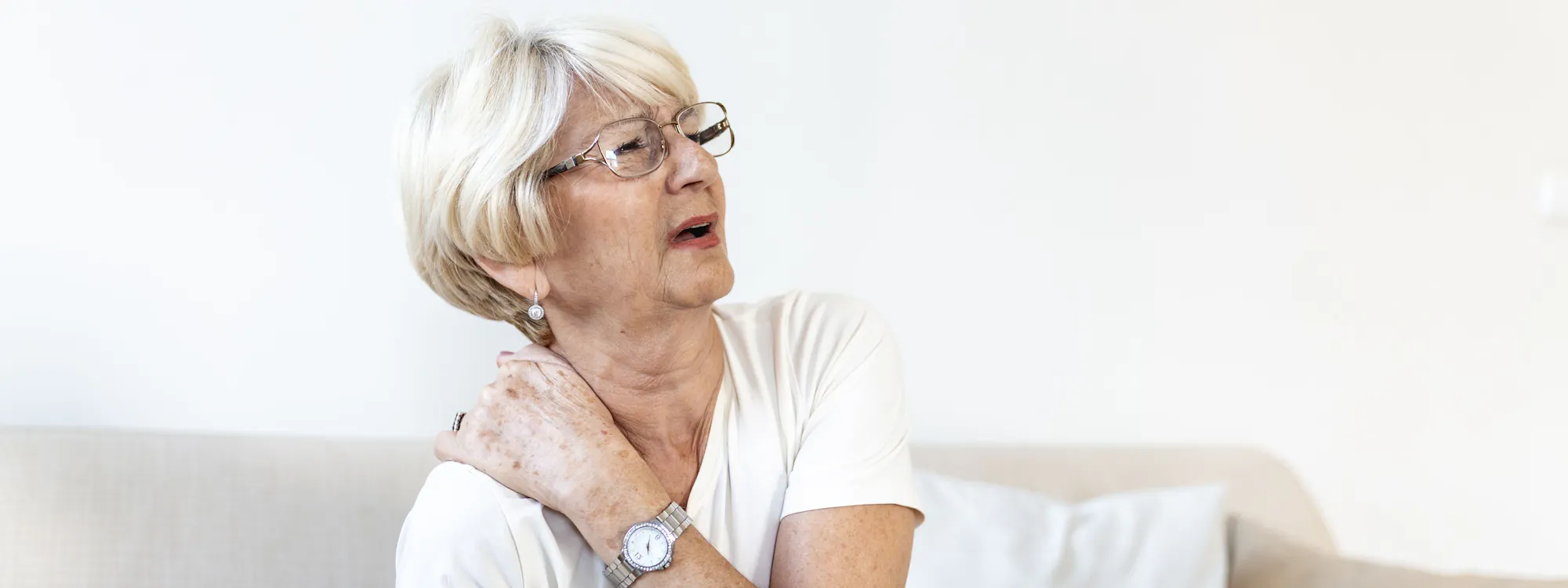 Fibromyalgie Patientin fasst sich mit schmerzverzerrtem Gesicht an den Nacken Fibromyalgie Patientin fasst sich mit schmerzverzerrtem Gesicht an den Nacken