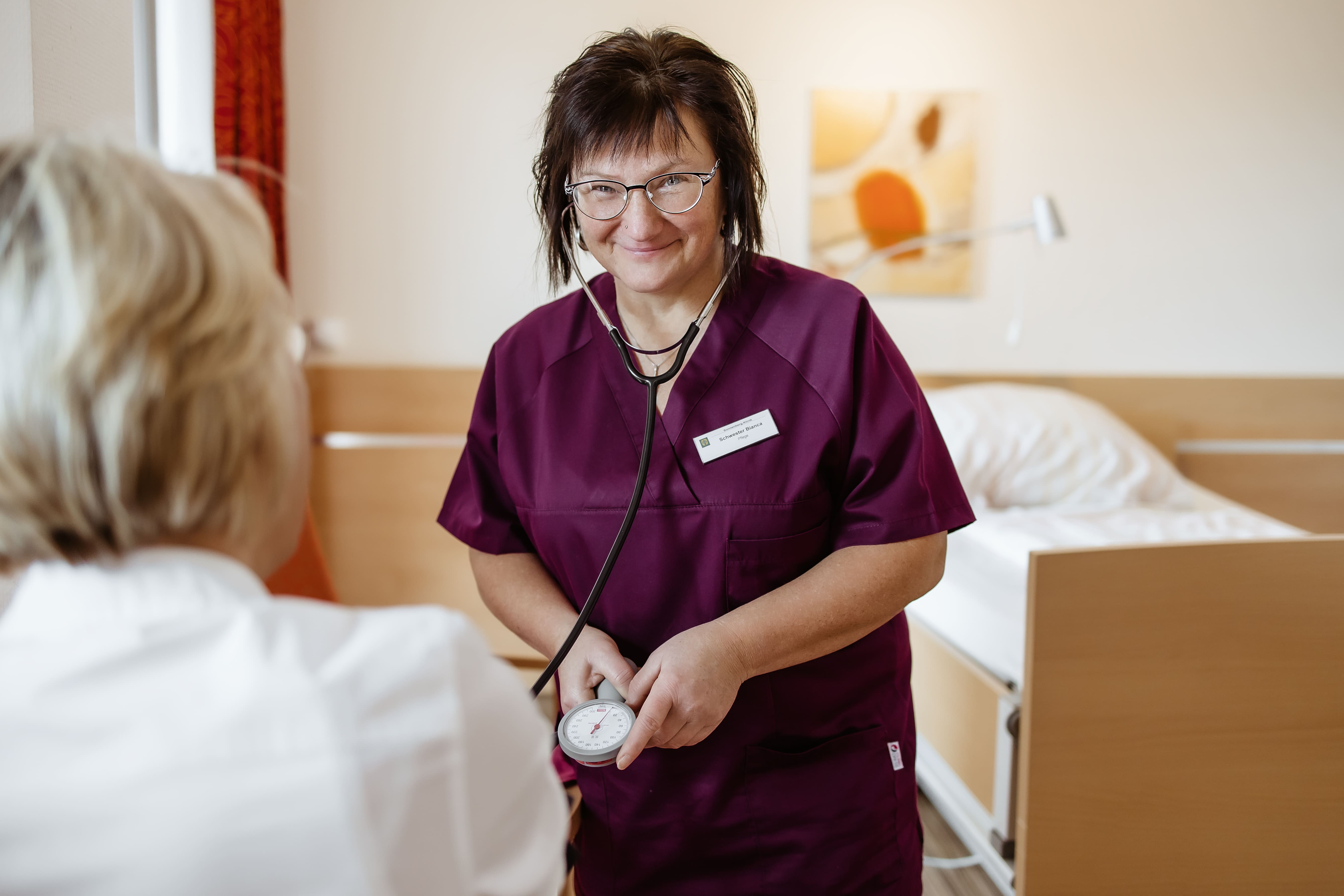 Mitarbeiterin der Klinik mit Krebspatientin im Zimmer