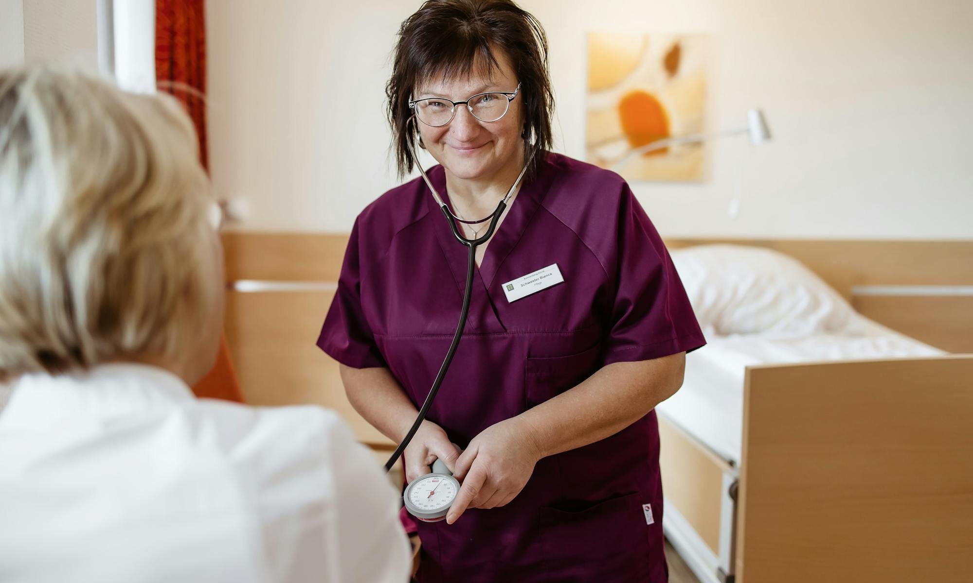 Mitarbeiterin der Klinik mit Krebspatientin im Zimmer