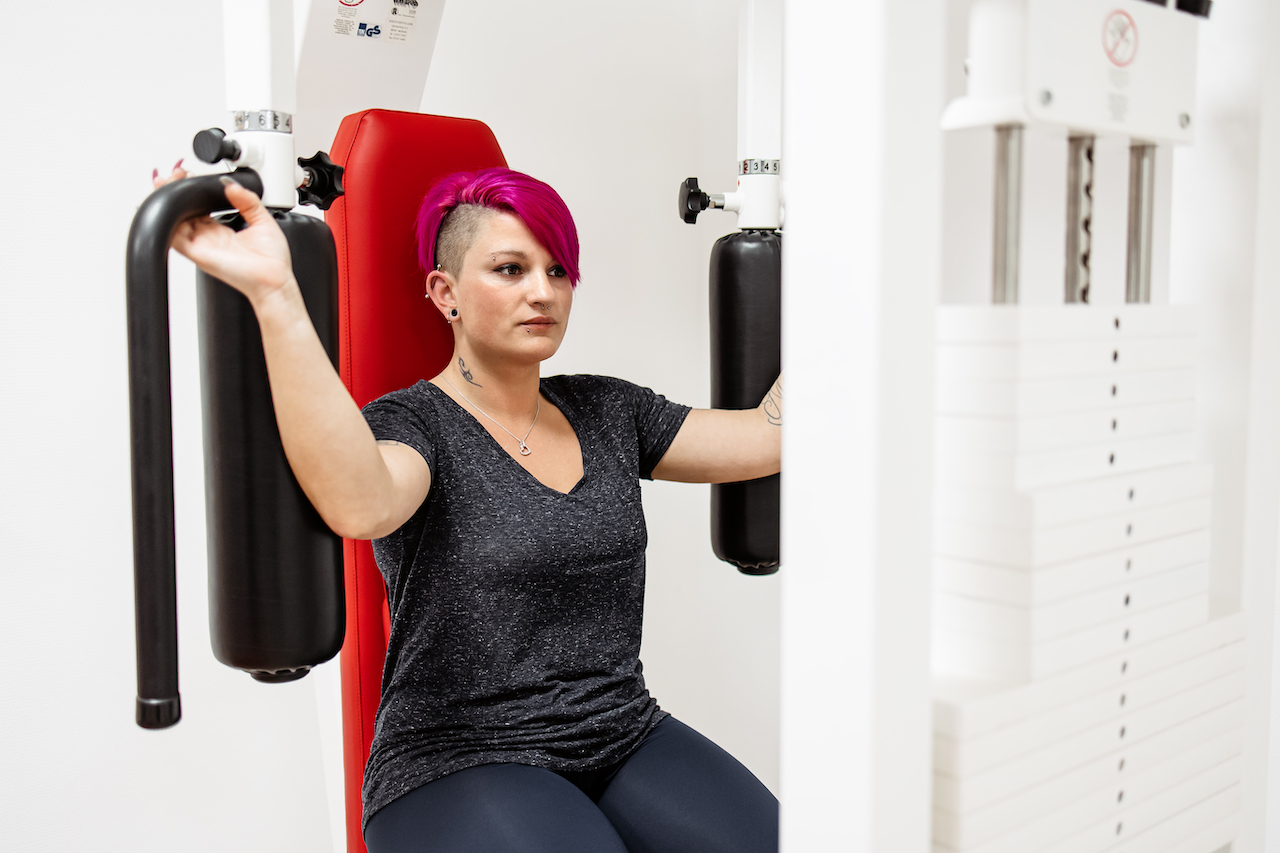 Patientin führt Übung an Sportgerät im Rahmen der onkologischen Rehabilitation durch
