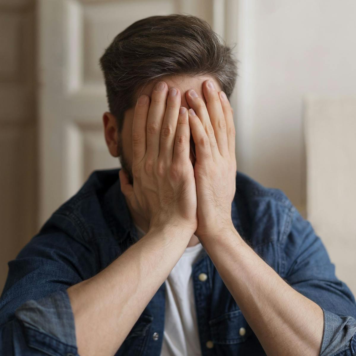 Mann mit Depressionen hält seine Hände vors Gesicht