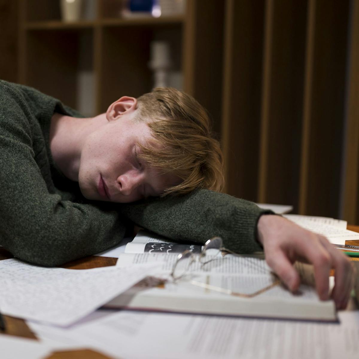 Junger Mann schläft mit dem Kopf auf dem Tisch ein