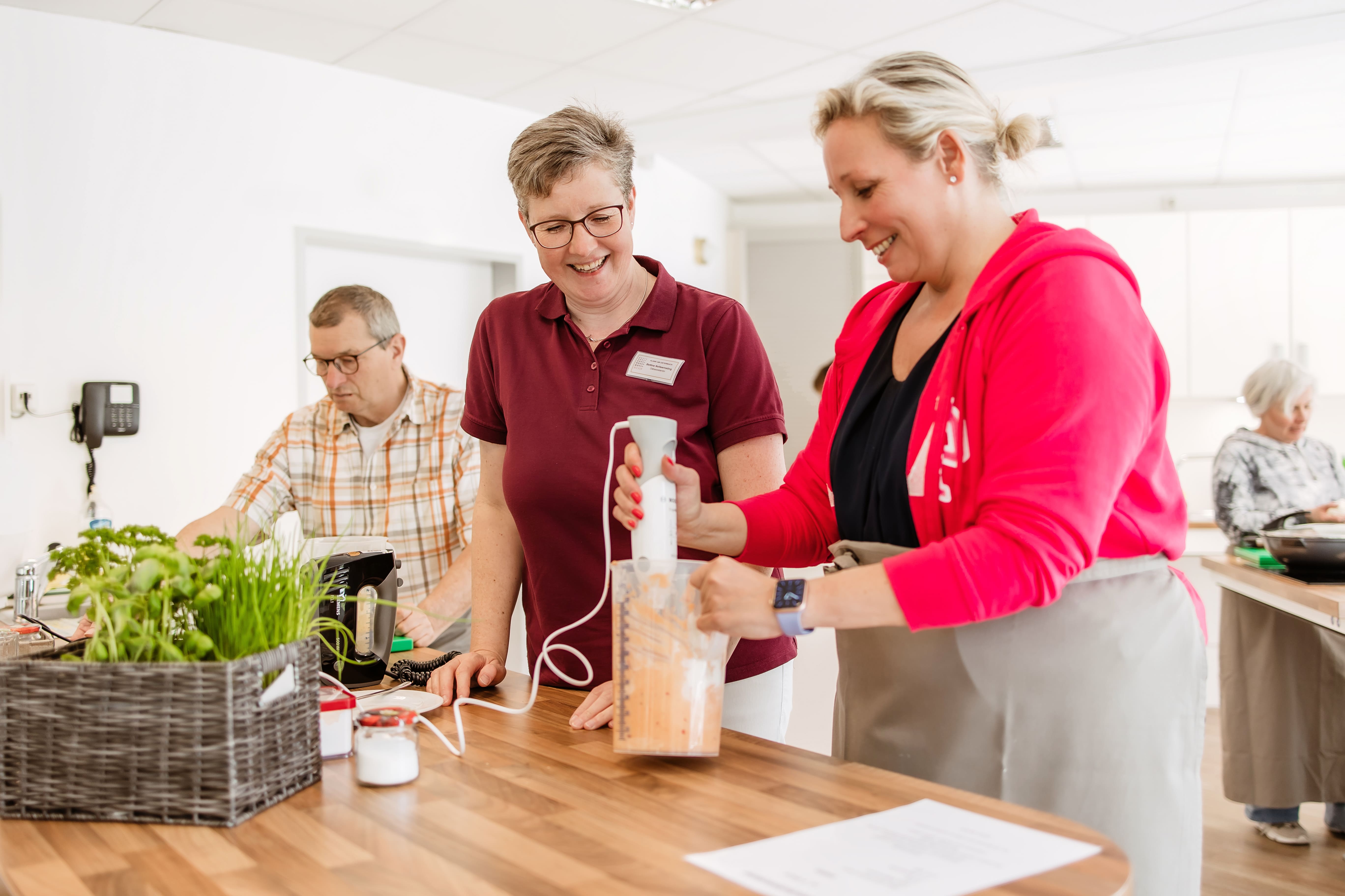 Therapeutin mit einem Patienten und einer Patientin in der Lehrküche