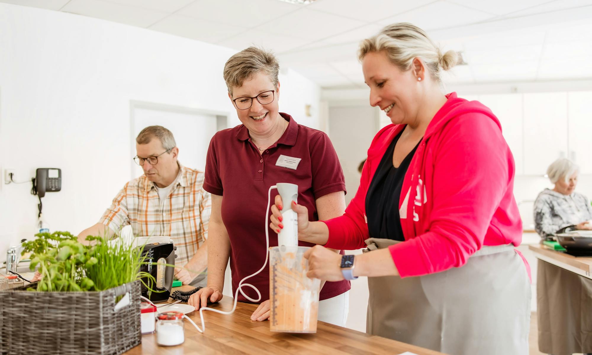 Therapeutin mit einem Patienten und einer Patientin in der Lehrküche