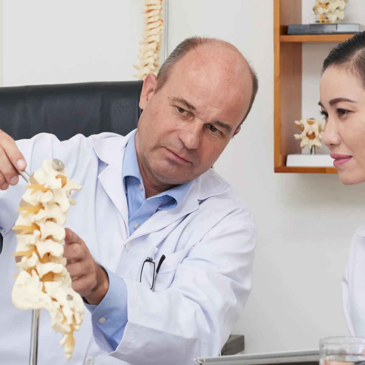 Arzt erklärt Verfahren anhand eines Wirbelsäulen Models