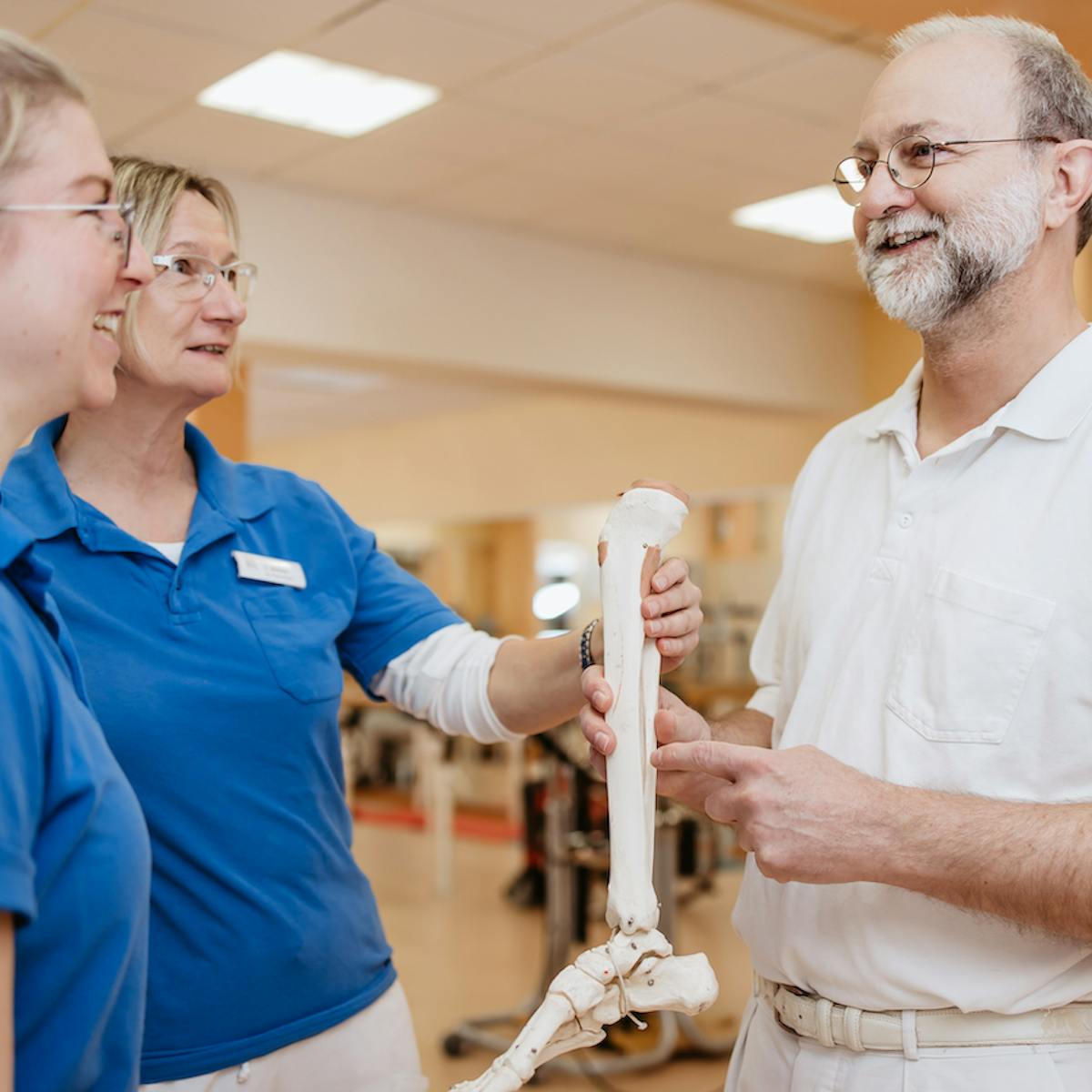 Orthopäde und zwei Therapeutinnen mit Knochen-Modell