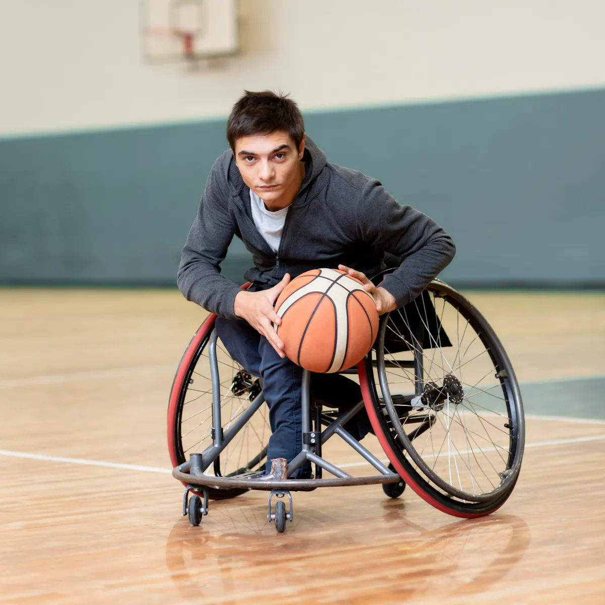Querschnittgelähmte Person spielt Basketball in einem Rollstuhl im Freizeitzentrum der Werner Wicker Klinik