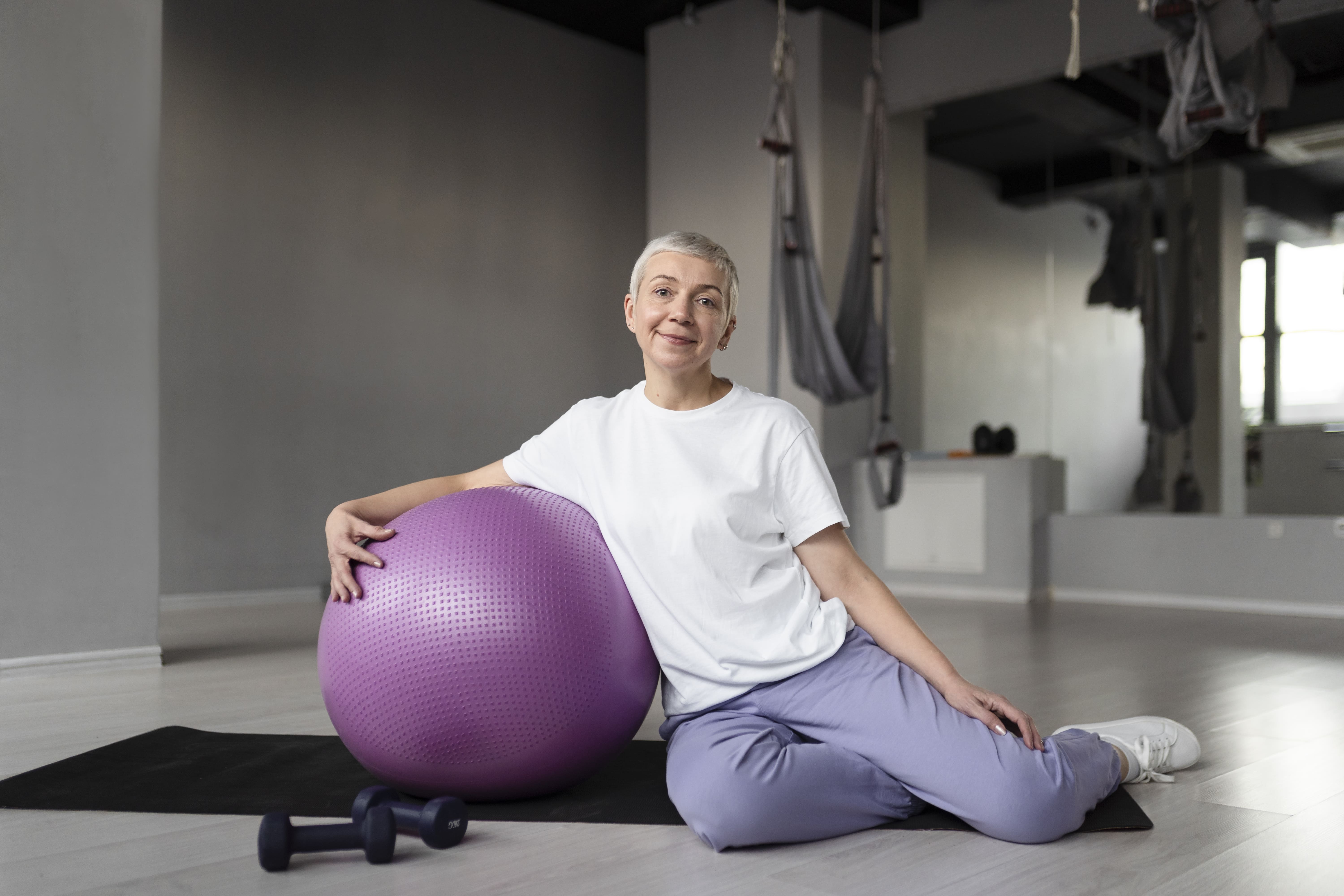 Patientin mit Gymnastikball bei der orthopädischen Bewegungstherapie