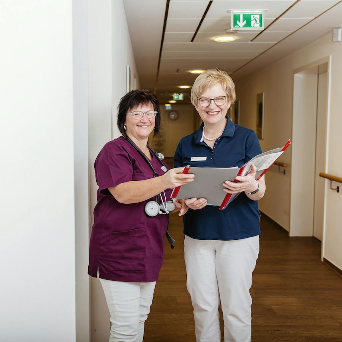 Zwei Mitarbeiterinnen der Sonnenberg-Klinik stehen nebeneinander und schauen eine Patientenakte an