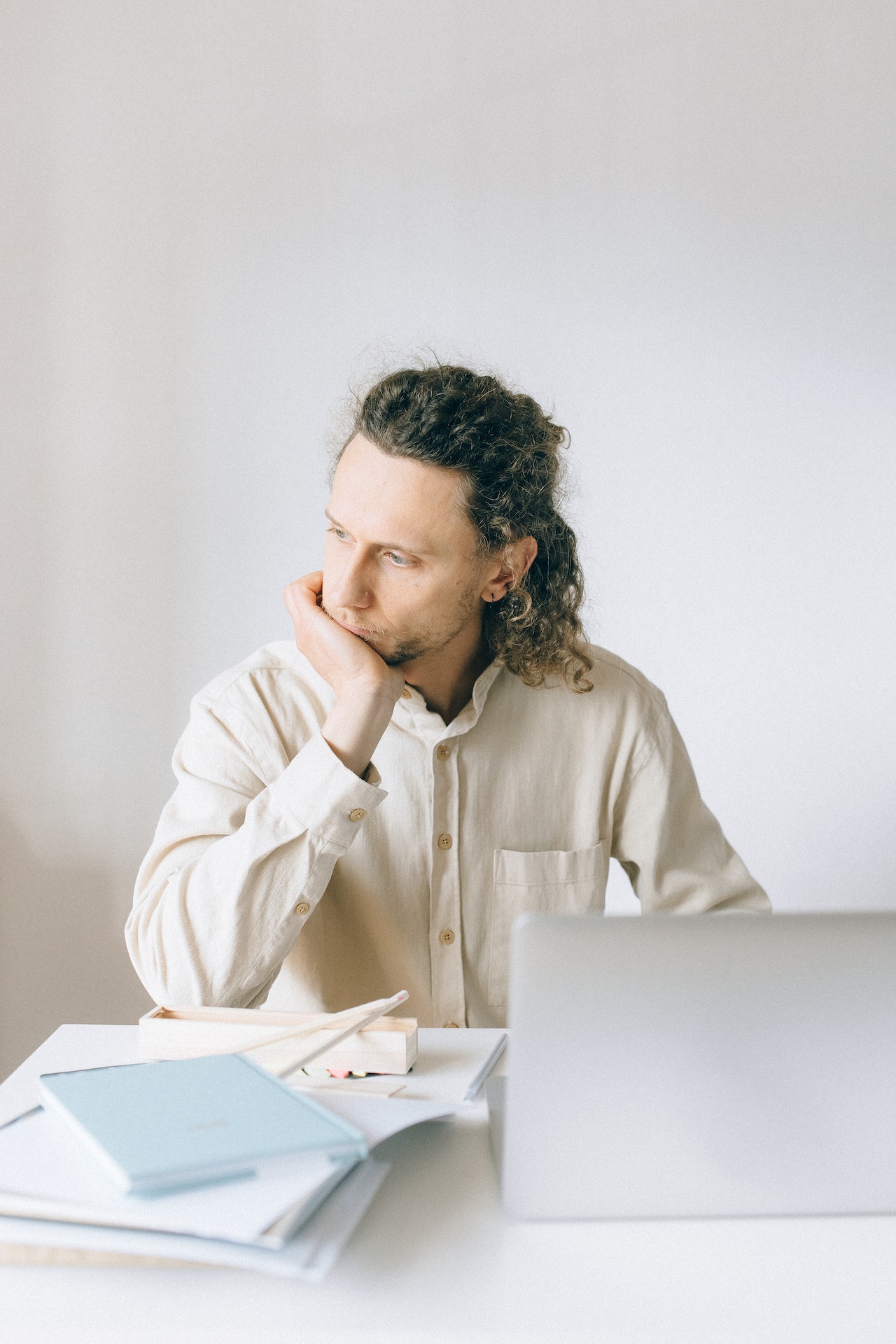 Mann sitzt erschöpft vor seinem Laptop und stützt sein Kinn auf die Hand