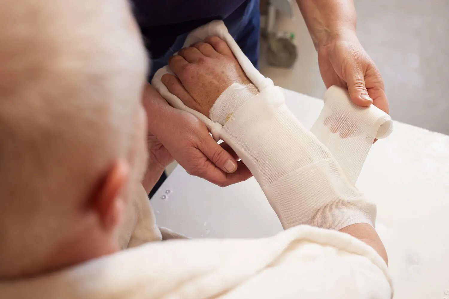 Arzt legt einen Verband um den gebrochenen Arm eines älteren männlichen Patienten