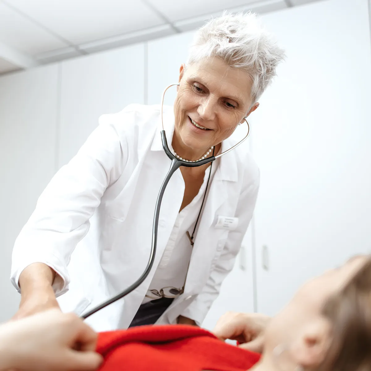 Ärztin bei der Untersuchung des Bauchraums über Patientin gebeugt