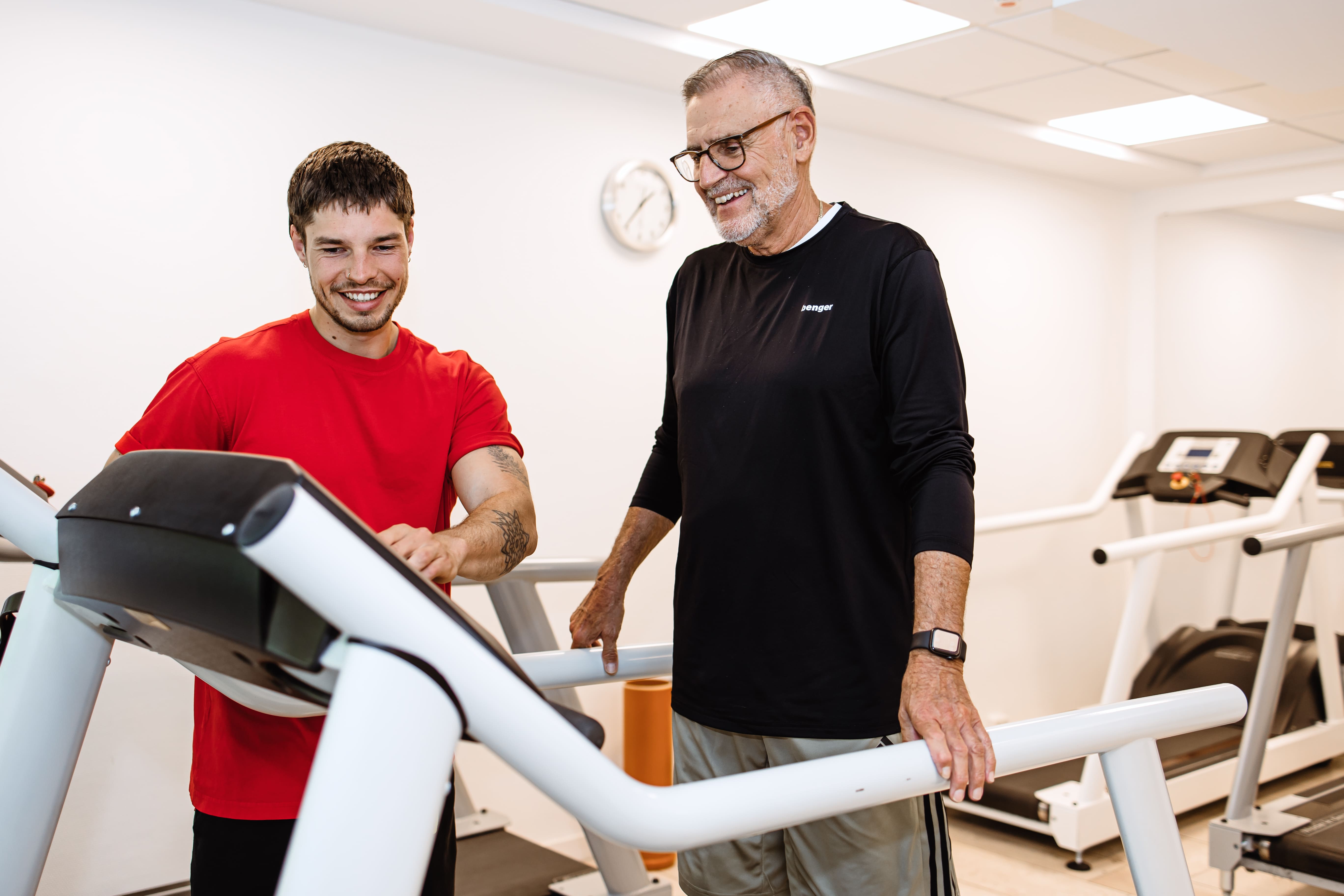 Physiotherapeut erklärt männlichem Patienten auf dem Laufband das Gerät