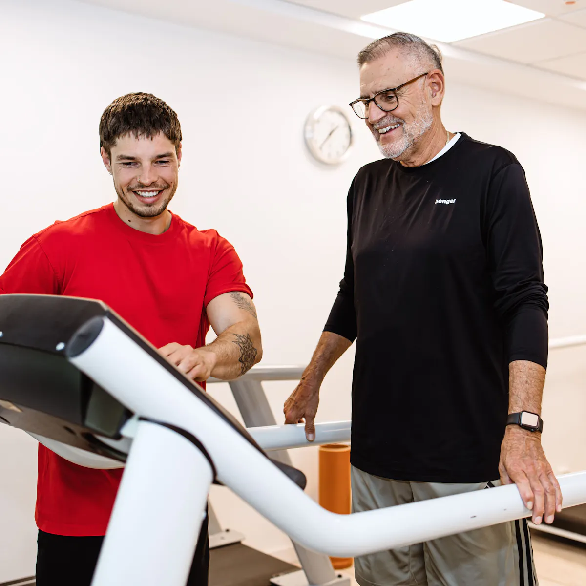 Physiotherapeut erklärt männlichem Patienten auf dem Laufband das Gerät