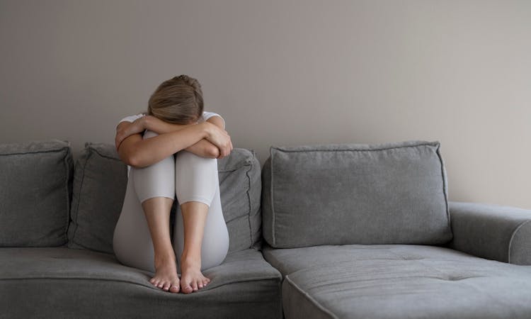 Traurige Frau sitzt auf Sofa